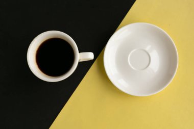 Geometrik sarı ve siyah arkaplanlı boş tabak ve kahve fincanı, üst manzara. Asgari konsept