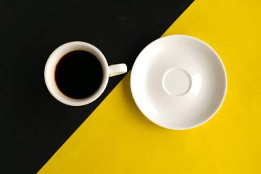 Geometrik sarı ve siyah arkaplanlı boş tabak ve kahve fincanı, üst manzara. Asgari konsept