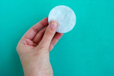 Mavi arkaplanda kadın eli pamuk süngeri, metin için kopyalama alanı, asgari konsept