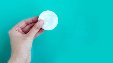 Mavi arkaplanda kadın eli pamuk süngeri, metin için kopyalama alanı, asgari konsept