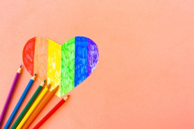 Lgbtq renklerindeki kalp ve pastel arkaplan üzerindeki kalemler, üst görünüm, boşluk kopyala