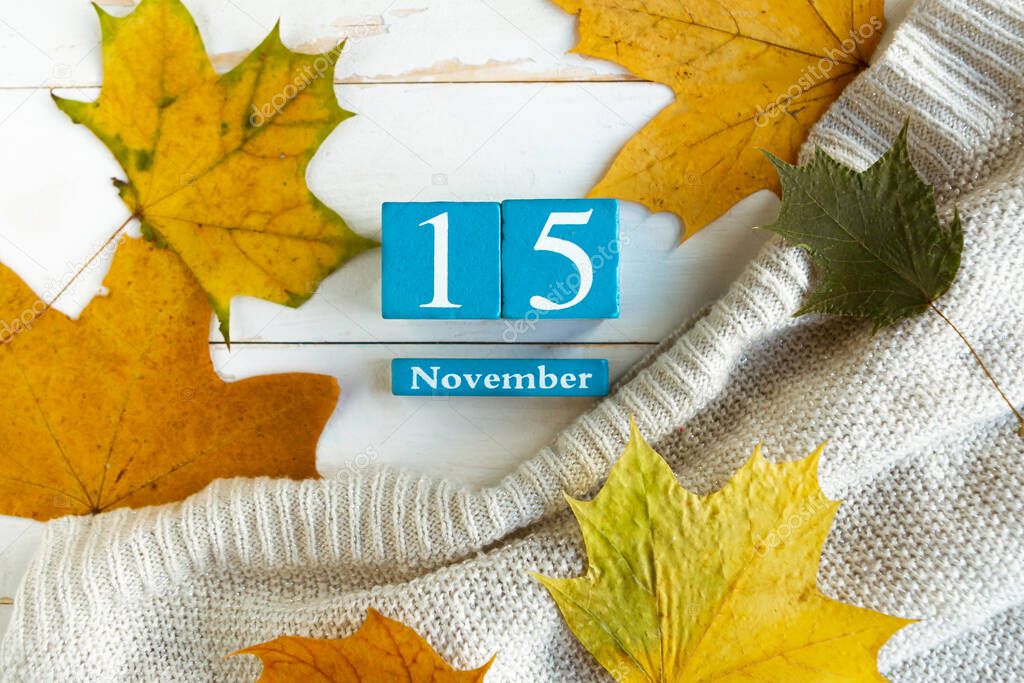 November 15. Blue cube calendar with month and date on wooden background