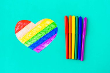 Lgbtq renklerinde kalemler ve mavi arkaplanda kalp, üst görünüm