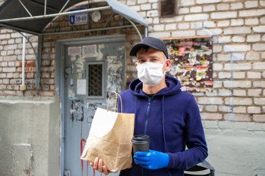 Koruyucu maskeli kurye paket yemek getiriyor. Coronavirus covid-19 salgını.
