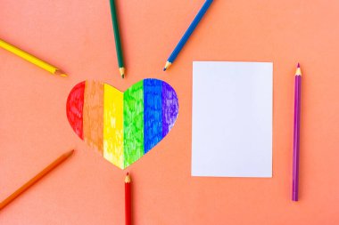 Lgbtq renklerinde kalemler ve pembe arkaplan üzerinde kalp, üst görünüm, metin için boş maket