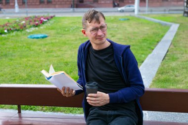 Genç adam parkta kitap okuyor, yakın çekim.