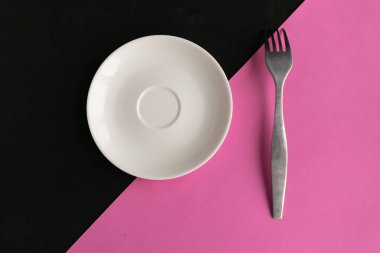 Pembe ve siyah geometrik arka planda boş tabak ve çatal. Metin için alanı kopyala. Asgari konsept