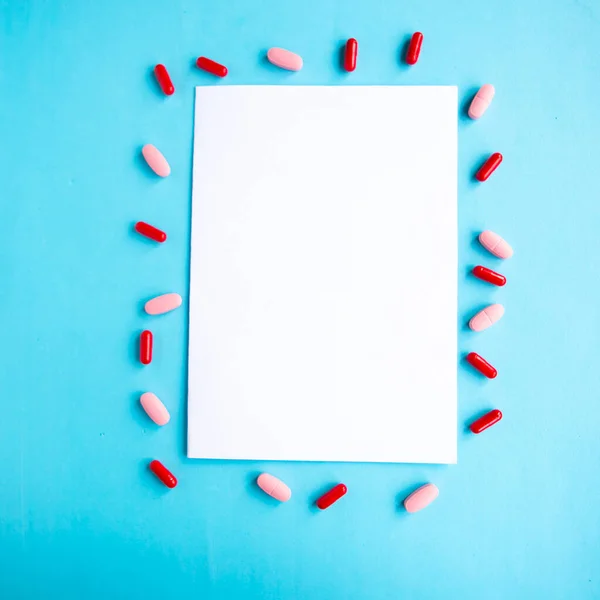 Medical pills and white mockup blank on blue background, top view