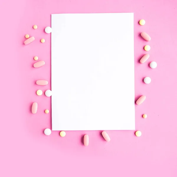 Medical pills and white mockup blank on pink background, top view