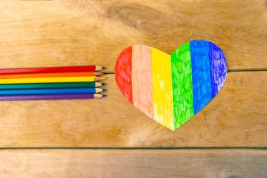 Lgbtq renklerinde kalemler ve tahta arka planda kalp, üst görünüm