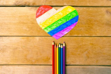 Lgbtq renklerinde kalemler ve tahta arka planda kalp, üst görünüm