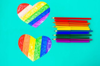 Lgbtq renklerinde iki kalp ve naneli arka planda kalemler, üst görünüm