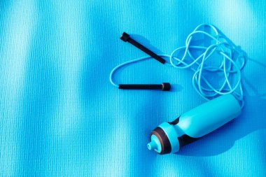 Atlama ipi, su şişesi ve spor paspası. Açık hava aktivitesi için gerekli malzemeler.