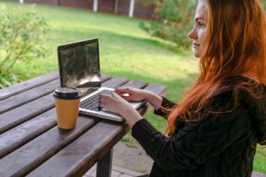 Doğada serbest çalışan biri. Kadın ormanda dizüstü bilgisayarla çalışıyor.. 