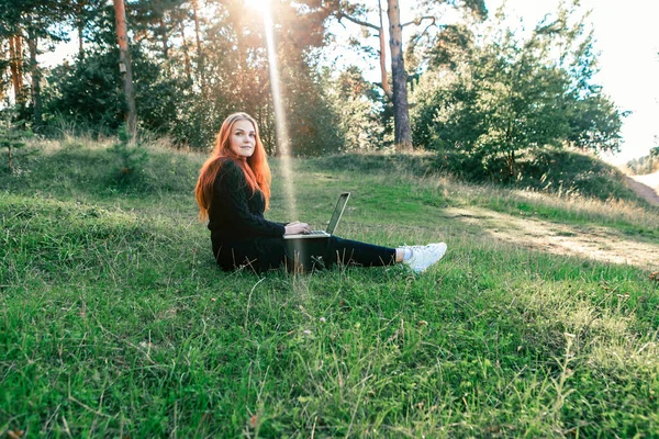 Freelancer in the nature. Woman is working on laptop in forest.