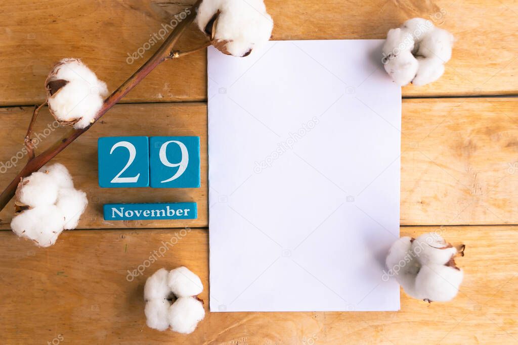 November 29. Blue cube calendar with month and date on wooden background.