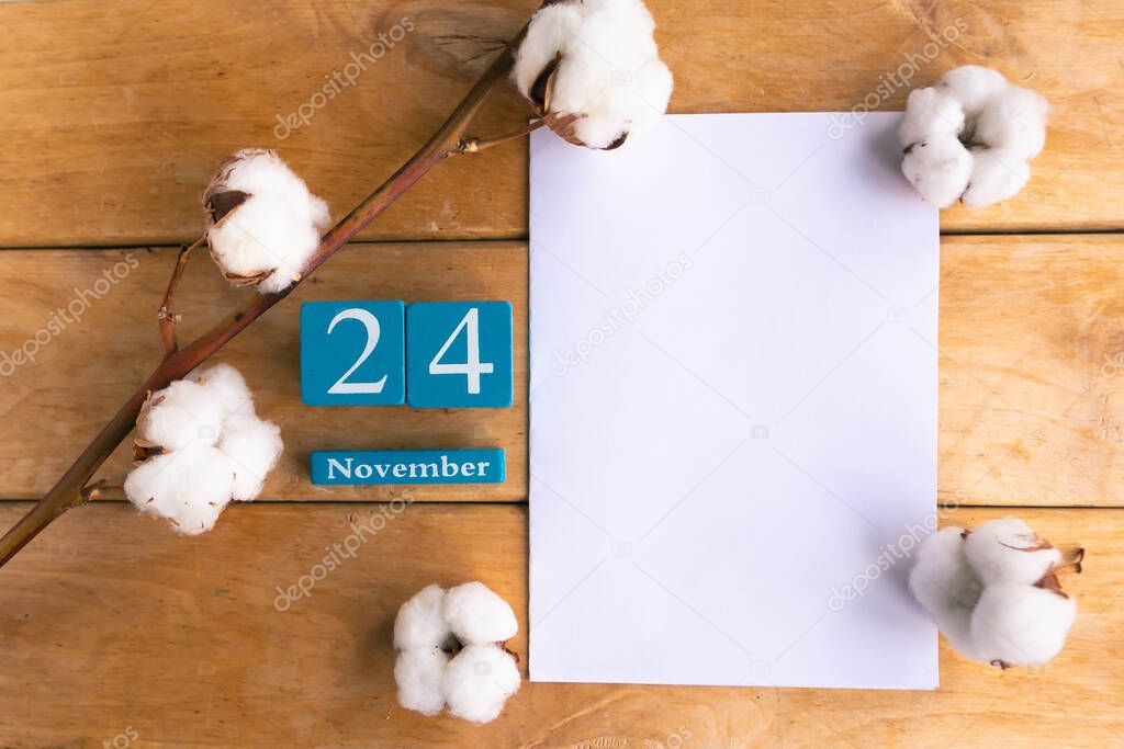 November 24. Blue cube calendar with month and date on wooden background.