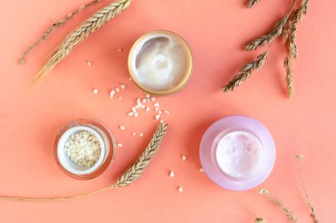 Buğday ve arpa doğal kozmetik. Kozmetik kavanozları ve pembe arka planda buğday kulakları.