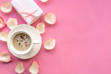 Kahve fincanı ve hediye paketi pembe arka planda, üst manzara