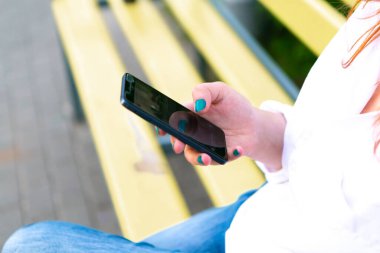 Kadının elinde cep telefonu var, yakın plan.