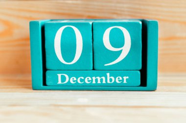 9 Aralık. Ahşap zemin üzerinde ay ve tarih olan mavi küp takvimi.