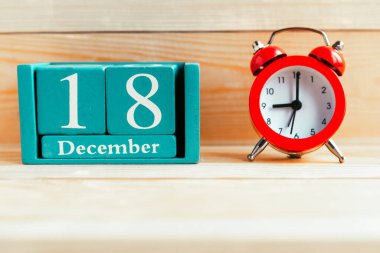 18 Aralık. Ahşap zemin üzerinde ay ve tarih olan mavi küp takvimi.