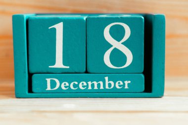18 Aralık. Ahşap zemin üzerinde ay ve tarih olan mavi küp takvimi.