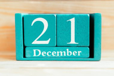 21 Aralık. Ahşap zemin üzerinde ay ve tarih olan mavi küp takvimi.