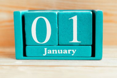 1 Ocak. Ahşap zemin üzerinde ay ve tarih olan mavi küp takvimi.