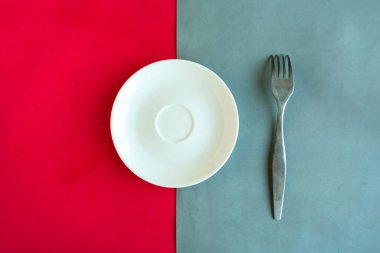 Renk geometrik arkaplanı üzerinde boş tabak ve çatal, minimal konsept, metin için kopyalama alanı