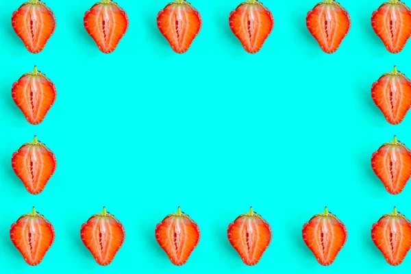 Sliced strawberry frame on blue background. Strawberry pattern, copy space for the text, minimal concept
