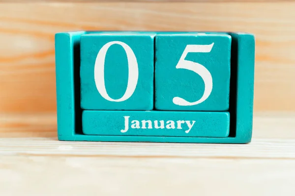 January 5. Blue cube calendar with month and date on wooden background.