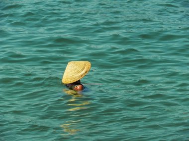 Vietnam şapkalı kadın denizde yüzüyor.