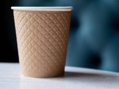 Metin veya reklam için yer ile bulanık bir arka plan ile ahşap bir masa üzerinde kahve plastik bir fincan götürün