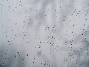 Bulanık arka planlı pencere camı yüzeyindeki yağmur damlaları