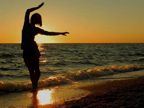 Sahilde gün batımında dans eden kaygısız bir kadın. Tatil canlılığı sağlıklı yaşam konsepti     