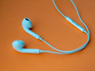 Beyaz kablolu kulaklıklar, turuncu arka planda kulaklık. Müzik günü