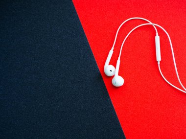 Beyaz kablolu kulaklıklar, siyah ve kırmızı arka planlı kulaklık. Müzik günü