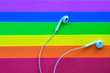Beyaz kablolu kulaklıklar, çok renkli gökkuşağı arka plan (lgbt) kulaklık. Müzik günü