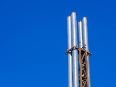 Mavi gökyüzüne karşı dört metal boru. Ekolojik sorunlar.