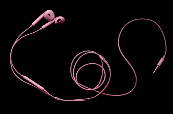 Pink wired headphones earbuds, headset on a black background. Music da