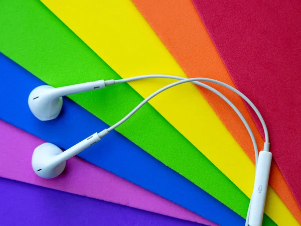 Beyaz kablolu kulaklıklar, çok renkli gökkuşağı arka plan (lgbt) kulaklık. Müzik günü