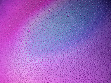 Camın üzerine renkli arka planda su damlacıkları. Su damlaları.