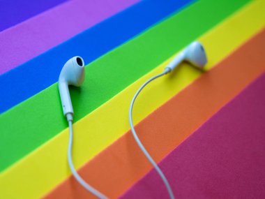 Beyaz kablolu kulaklıklar, çok renkli gökkuşağı arka plan (lgbt) kulaklık. Müzik günü