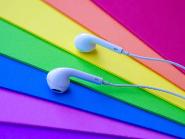 Beyaz kablolu kulaklıklar, çok renkli gökkuşağı arka plan (lgbt) kulaklık. Müzik günü