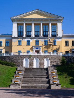 İskeledeki adam eski sarı bir binayı onarıyor.