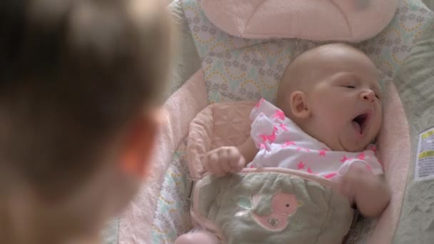 ロッキングチェアで寝る赤ちゃんの妹を落ち着かせる兄 — ストック動画