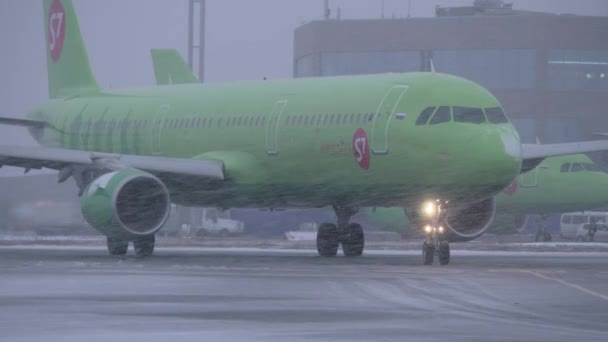 Plane of S7 Airlines driving on runway at Domodedovo Airport, view in snowfall — Stock Video