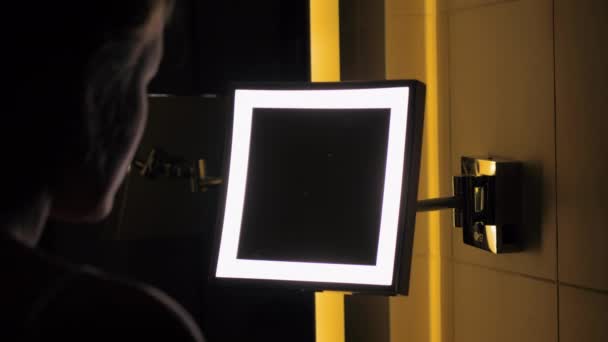 Frau blickt auf Badezimmerspiegel und trägt Nachtcreme auf — Stockvideo