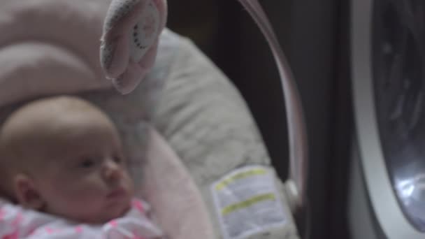 Bébé fille regardant la machine à laver couché dans le siège gonflable — Video